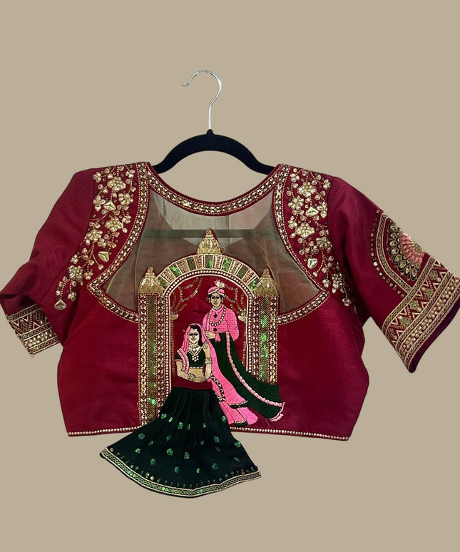 House Of Indian Wedding Attire maroon silk-like blouse with gold embroidery and sheer yoke, paired with a dark green skirt.