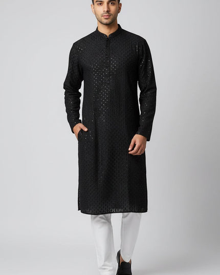 Man wearing a black Kurti Connection USA embroidered kurta with a mandarin collar and side pockets over white trousers