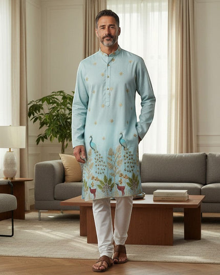 Kurti Connection USA light blue silk kurta set with intricate peacock embroidery and white pajama, worn by a man.