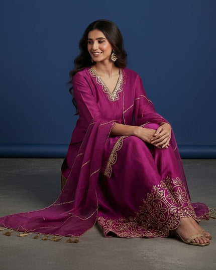 Kurti Connection USA magenta silk sharara suit with gold embroidery on neckline, sleeves, and hem. Sheer dupatta with tassels.