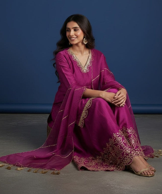Kurti Connection USA magenta silk sharara suit with gold embroidery on neckline, sleeves, and hem. Sheer dupatta with tassels.