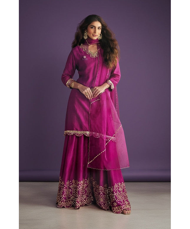 Kurti Connection USA magenta silk sharara suit with gold embroidery and sheer dupatta. Model wears ornate earrings and bracelet.