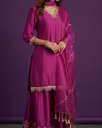 Kurti Connection USA magenta silk sharara suit with gold embroidery on neckline, sleeves, and hem. Sheer dupatta with tassels.