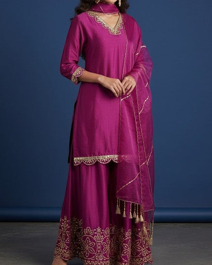 Kurti Connection USA magenta silk sharara suit with gold embroidery on neckline, sleeves, and hem. Includes dupatta with tassels.