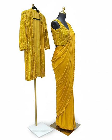 Kurti Connection USA mustard yellow saree with ruffle border, sleeveless blouse, and sequin-embellished long shrug.