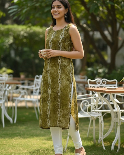 Kurti Connection USA sleeveless olive green printed straight kurti with white leggings and gold sandals, worn by a woman outdoors.