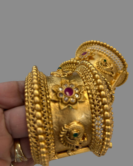 Kurti Connection USA ornate gold-tone bangle with floral motifs, peacock detailing, and ruby and emerald accents.