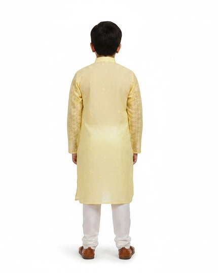 Back view of a boy wearing a Kurti Connection USA yellow embroidered kurta with white churidar trousers