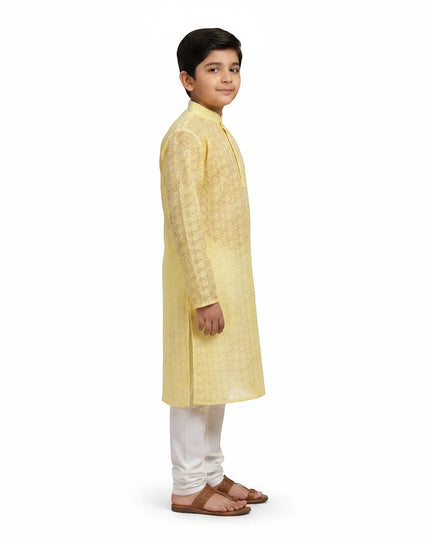 Kurti Connection USA boy wearing a yellow embroidered kurta with white churidar trousers in a side profile view.